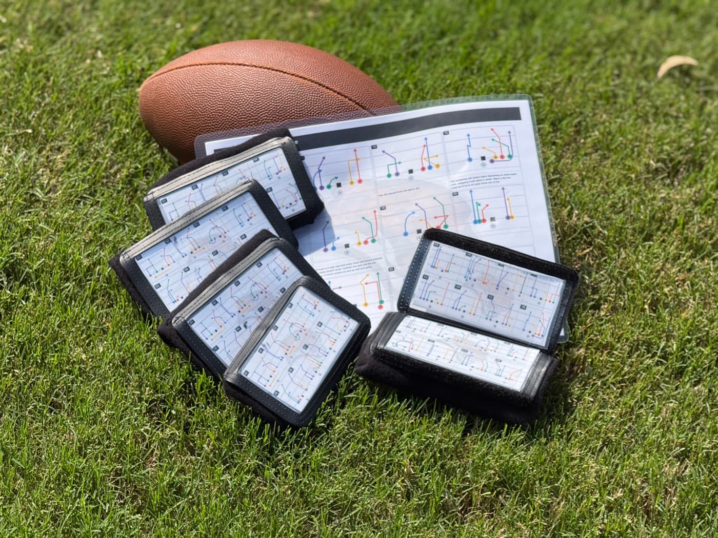 Printed call sheet and four wristbands on the field — generated from a real xogridmaker playbook